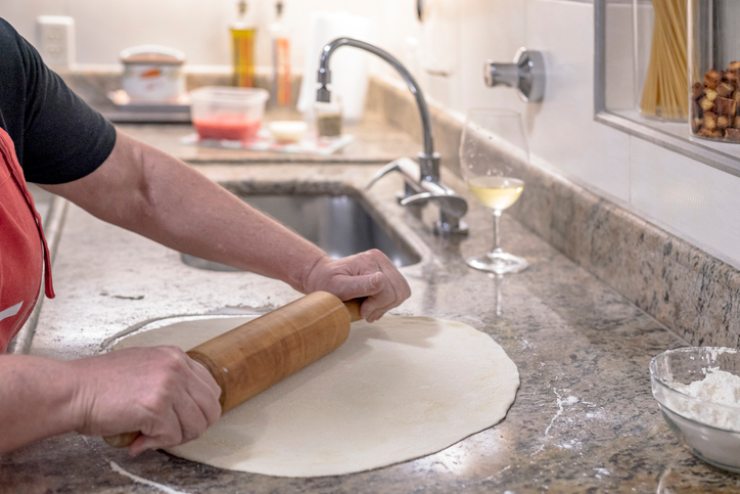 Un pasticciere stende la pasta con un mattarello