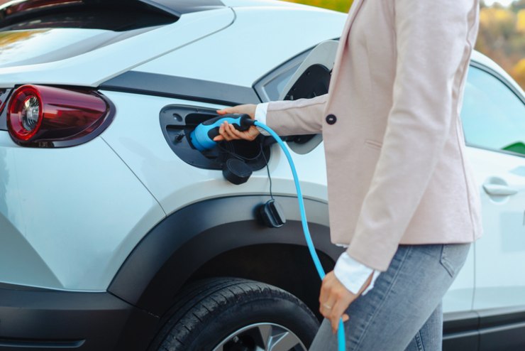 Una donna mentre ricarica la sua auto elettrica