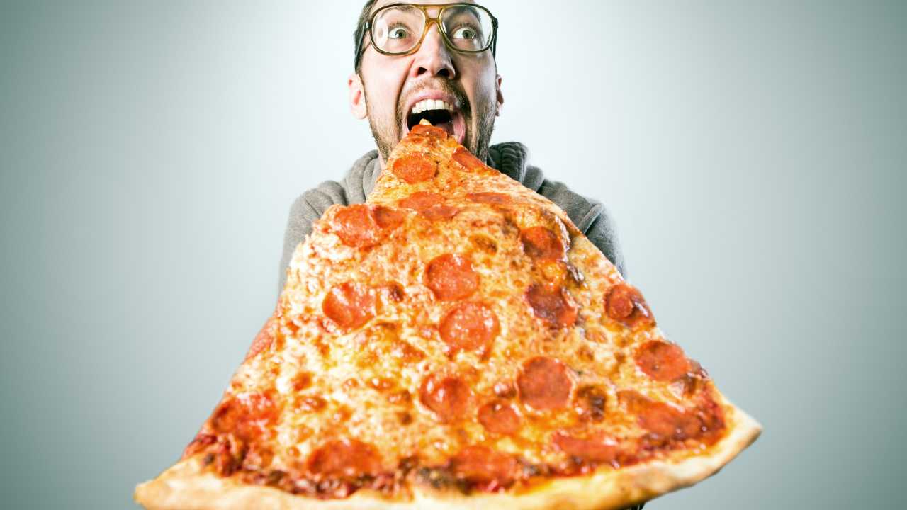 Un uomo mangia una pizza gigante