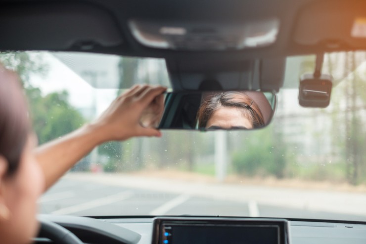Una donna regola lo specchietto della sua auto