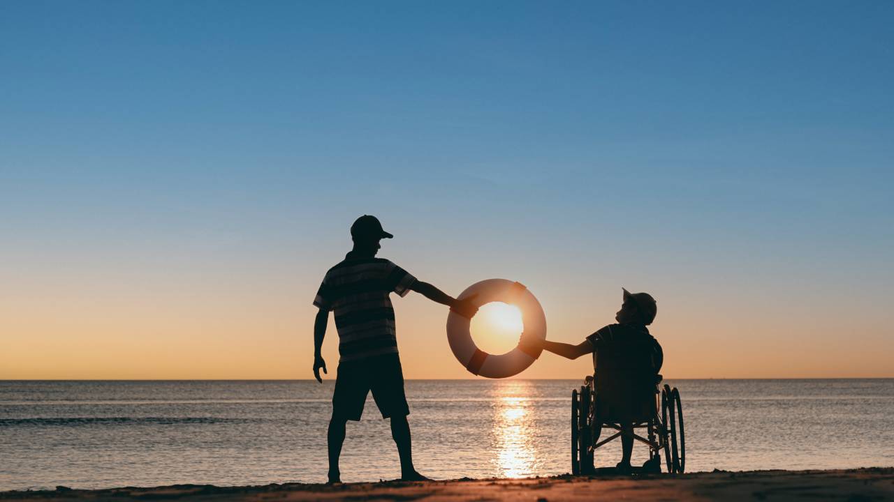 Un disabile e il suo caregiver su una spiaggia