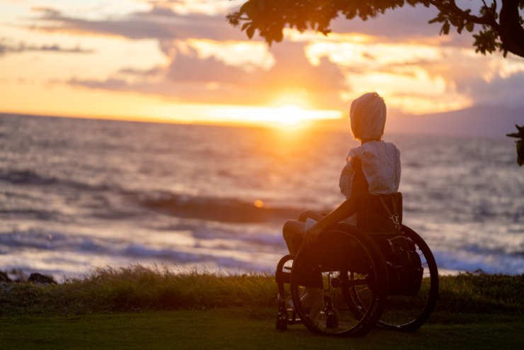 Una donna su una sedia a rotelle guarda il tramonto