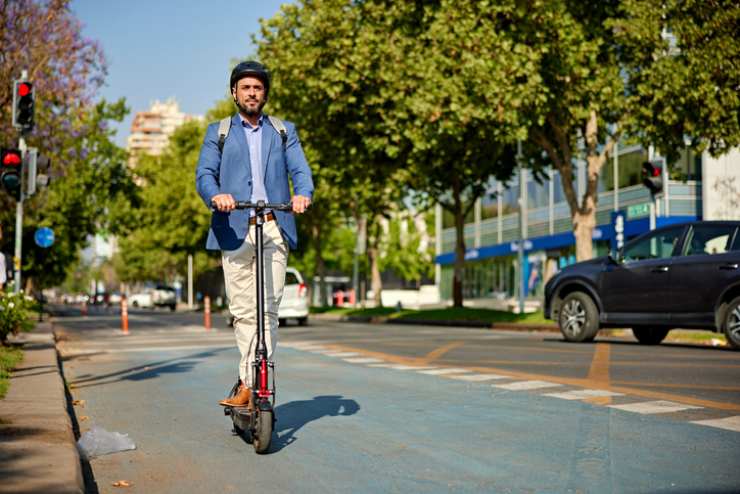 Un uomo va al lavoro con un monopattino elettrico