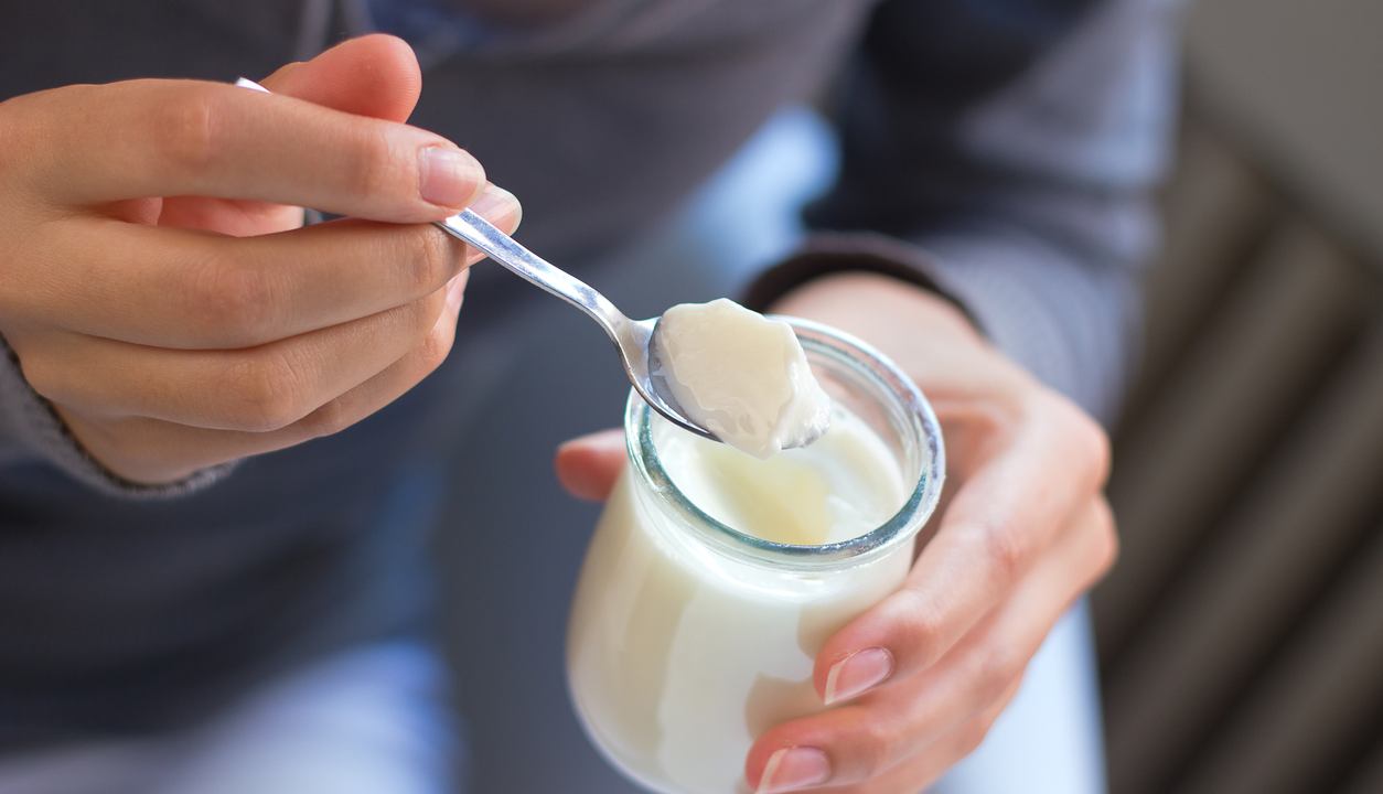 Una donna mangia dello yogurt in casa 