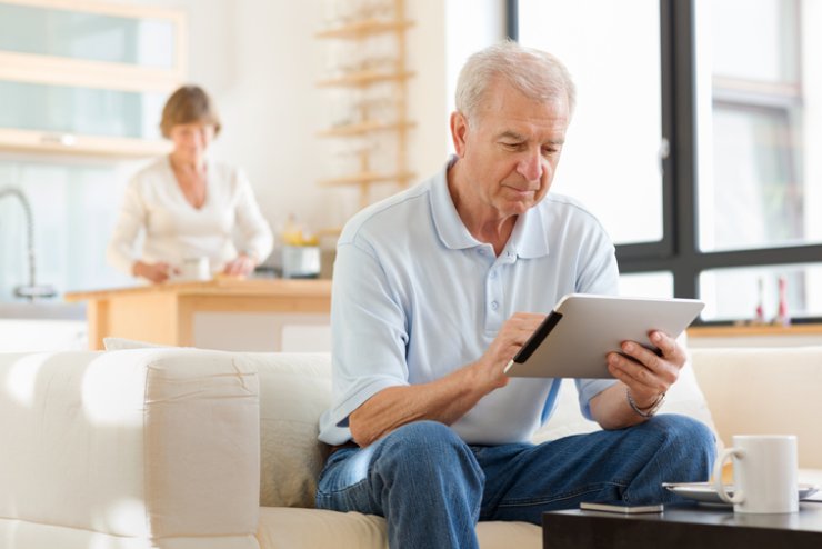 Un anziano consulta un tablet sul divano