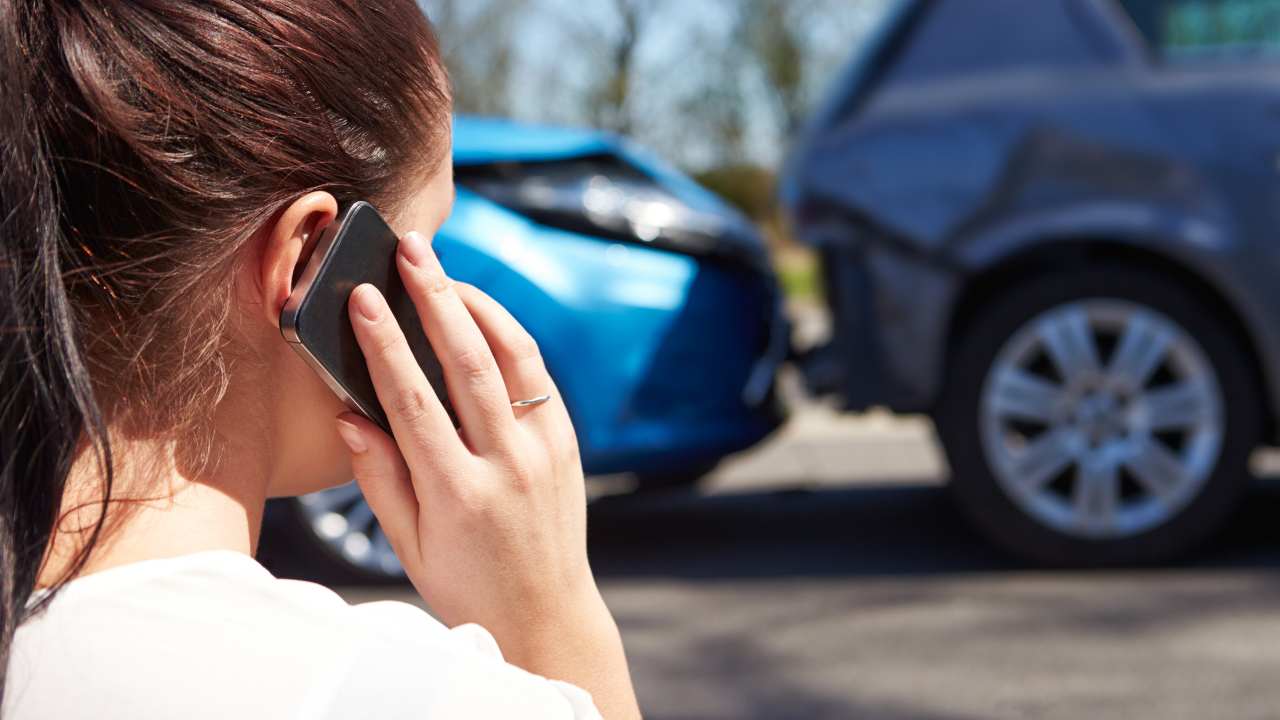 Una donna telefona dopo un incidente stradale