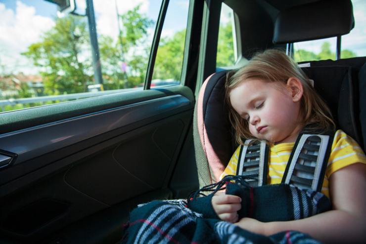 Una bambina dorme in auto