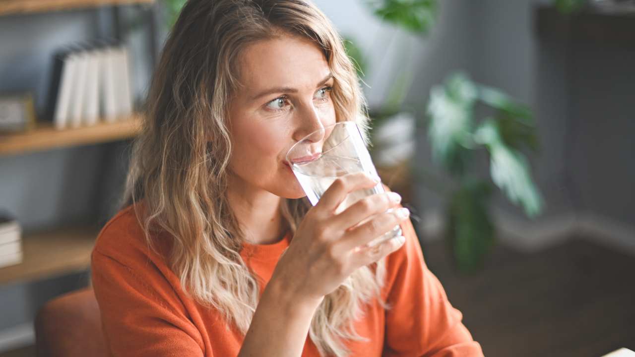Una donna beve dell'acqua da un bicchiere