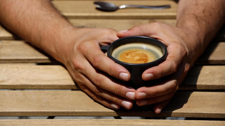 Un uomo tiene in mano una tazza di caffè