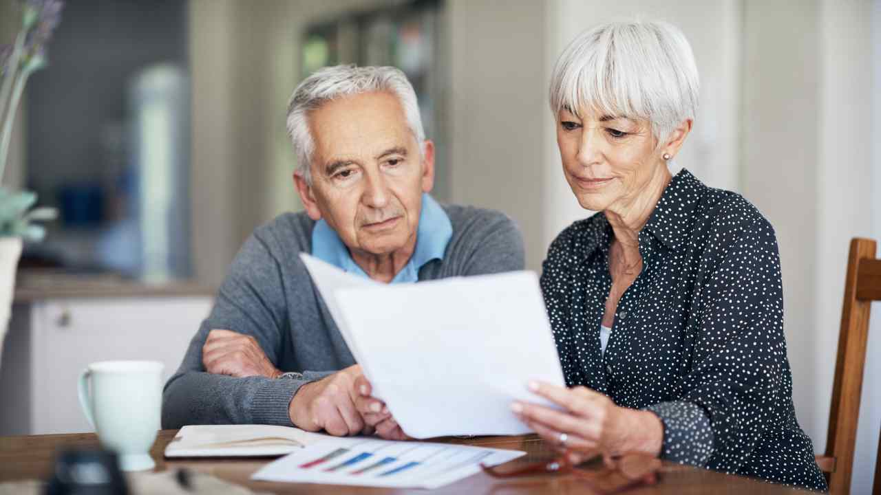 Una coppia di anziani consulta un documento fiscale