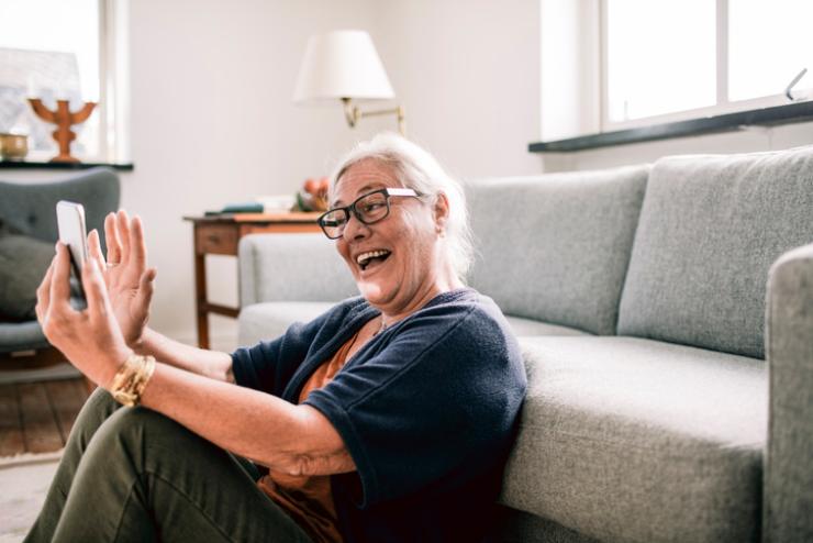 Una pensionata in casa con lo smartphone