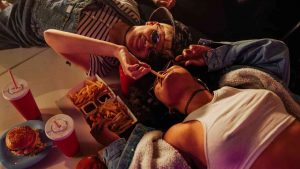 Donne sdraiate sul cofano mangiano patatine