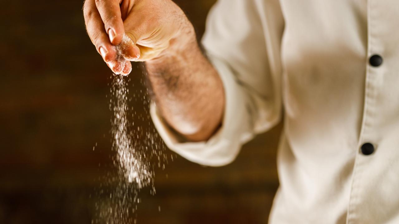 Un uomo getta del sale in un piatto